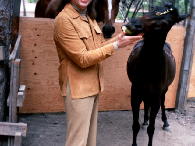 Photo of Adi Da Samraj laughing and feeding an apple to a horse